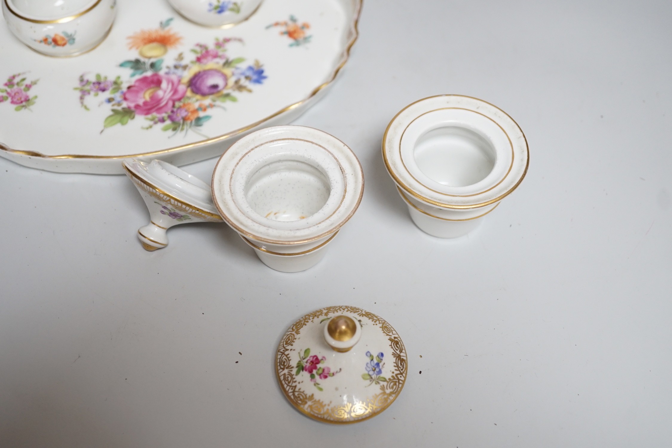 A 19th century German Inkstand with two pots and covers painted with flowers, 24cm wide, and a Volkstedt figure of an eastern European woman holding a bird	